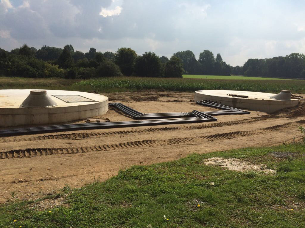 Mehrere neu gebaute Rundbecken einer Kläranlage auf freiem Gelände während der Bauphase.