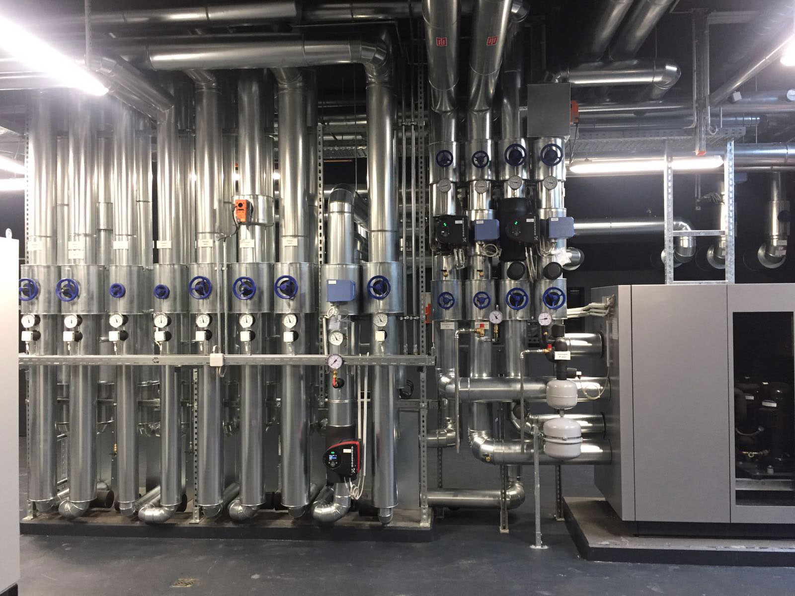 Große technische Anlage mit Pumpen, Ventilen und Rohrleitungen in einem Maschinenraum.